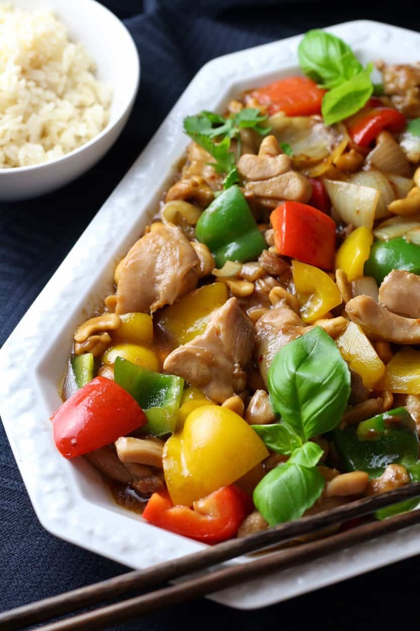Cashew Chicken on a serving platter with peppers, onions, cashews and rice. With basil and coriander.