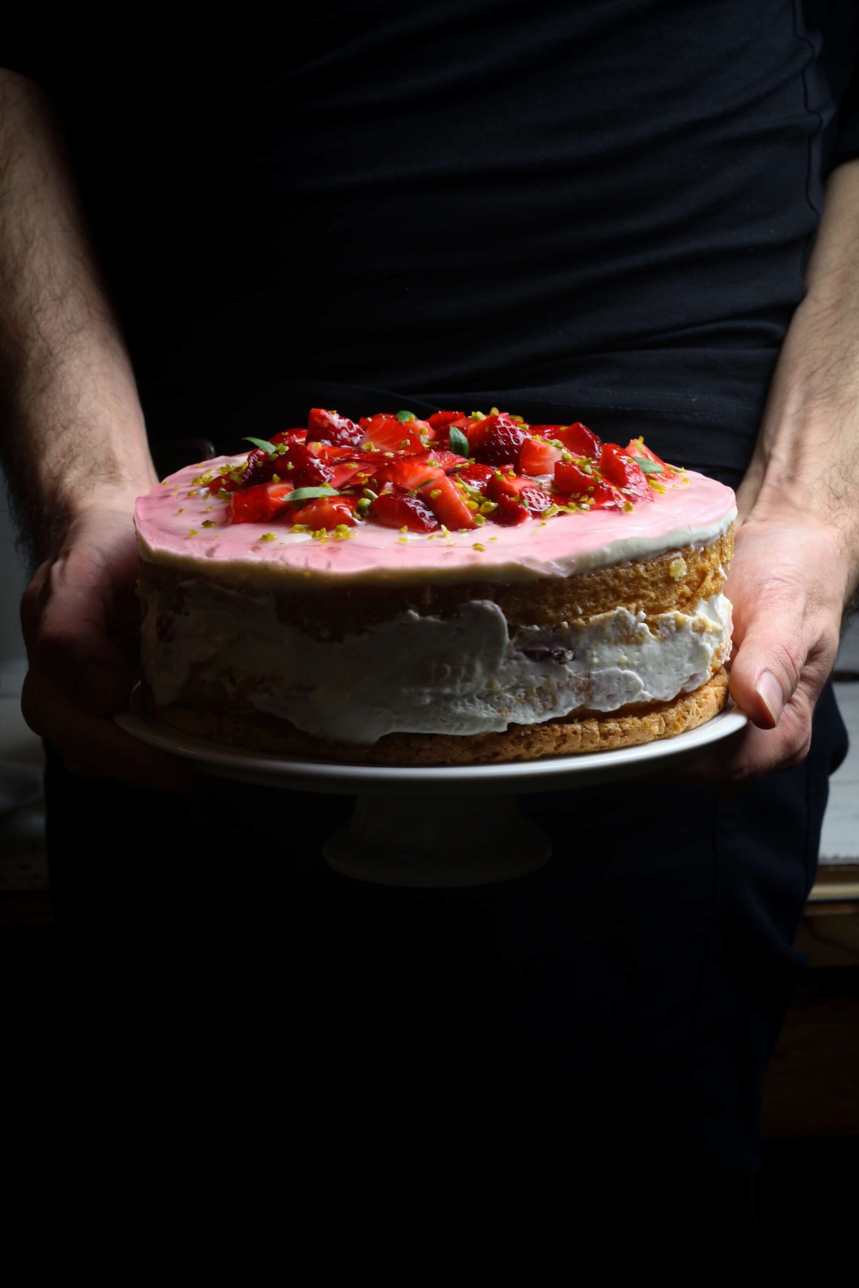 Hands holding a German Strawberry Cream Torte.