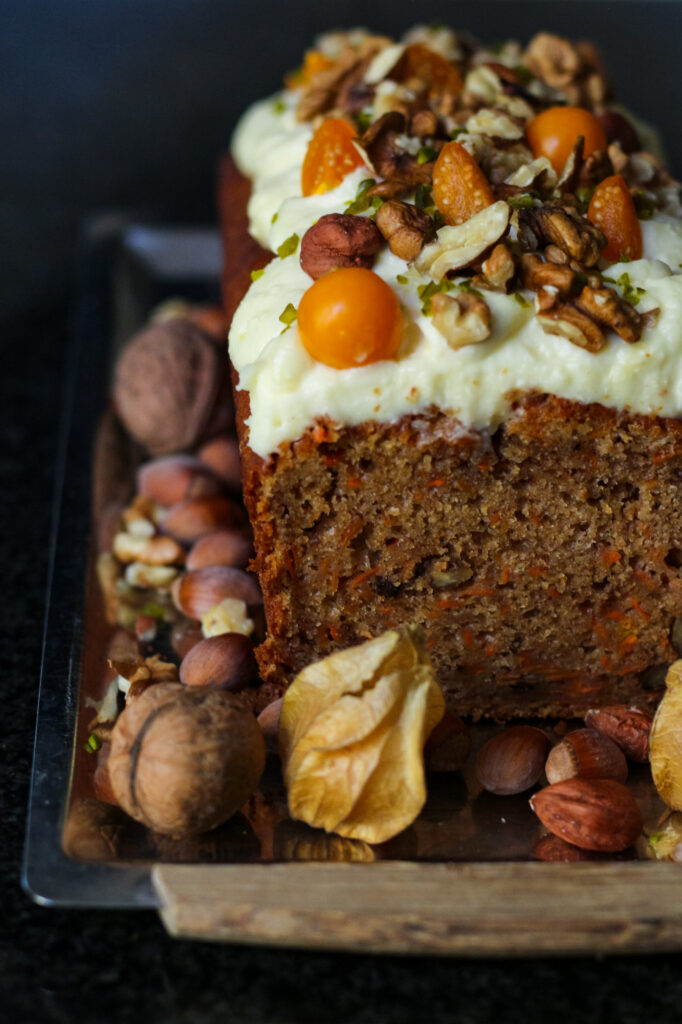 Easy Carrot Cake Loaf with cream cheese frosting and a topping of nuts and fresh fruit.