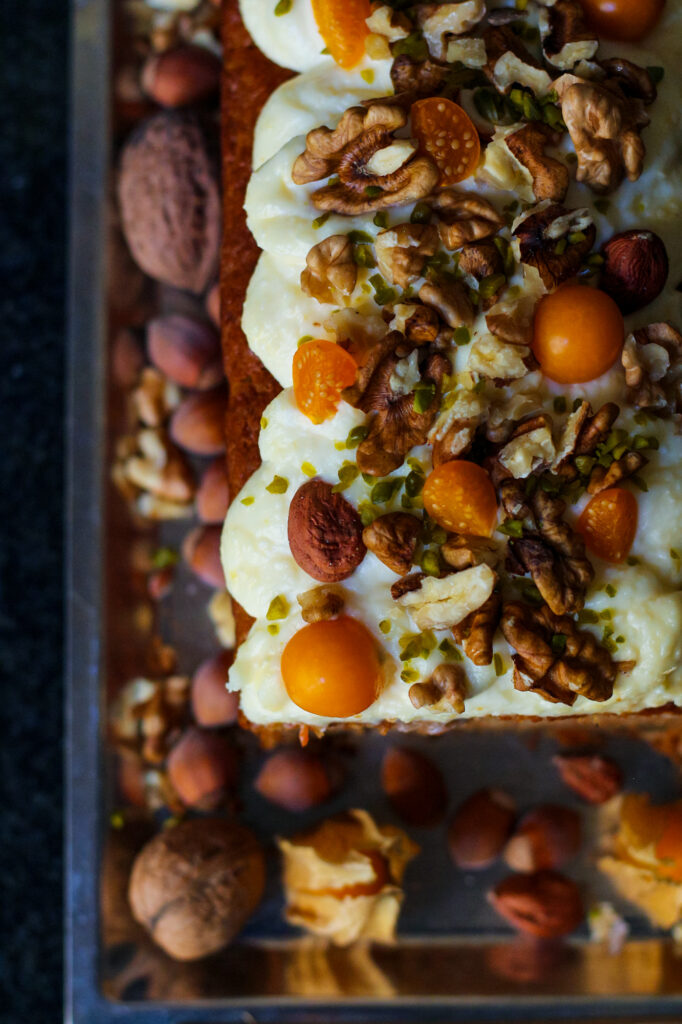 Easy Carrot Cake Loaf with cream cheese frosting and a topping of nuts and fresh fruit.