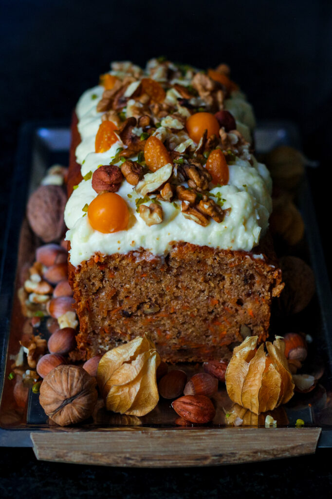 Easy Carrot Cake Loaf with cream cheese frosting and a topping of nuts and fresh fruit.