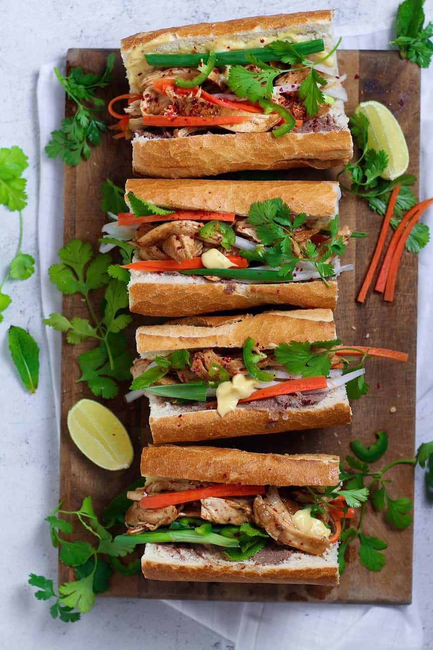 Stack of delicious Banh Mi sandwiches on a wooden board.