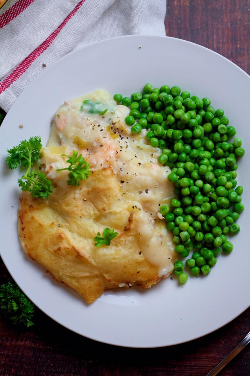 Creamy Smoked Fish Pie on a plate with peas.