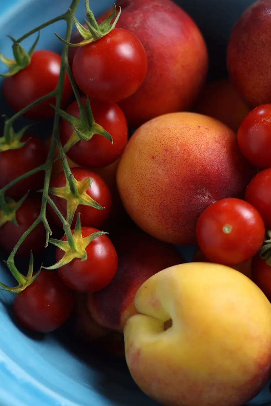 Tomatoes and fresh peaches in a blue bowl
