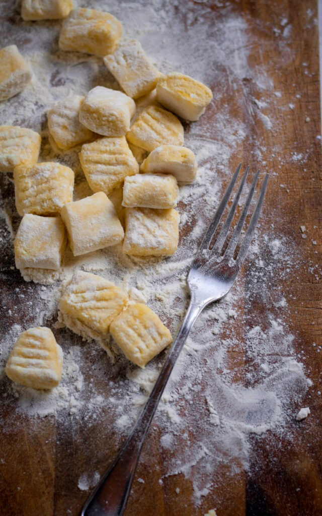 Sliced and pressed gnocchi on a board with a fork.