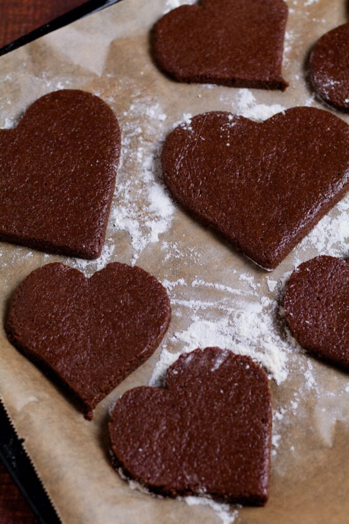 Unbaked gingerbread hearts on a baking tray.