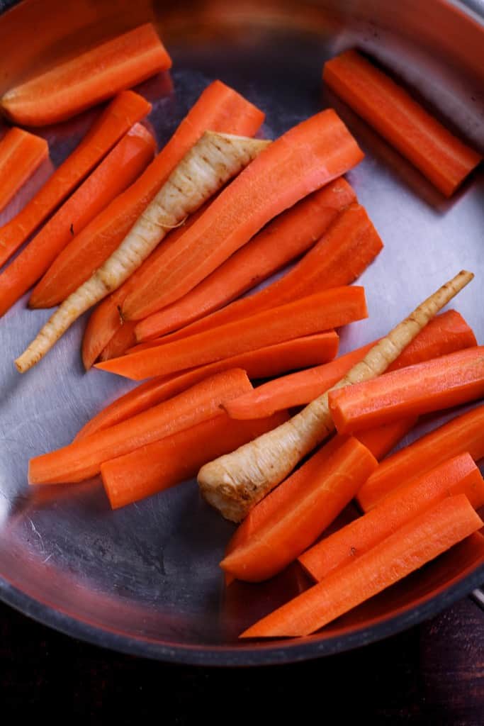 Carrots batons and parsnips in a roasting pan.