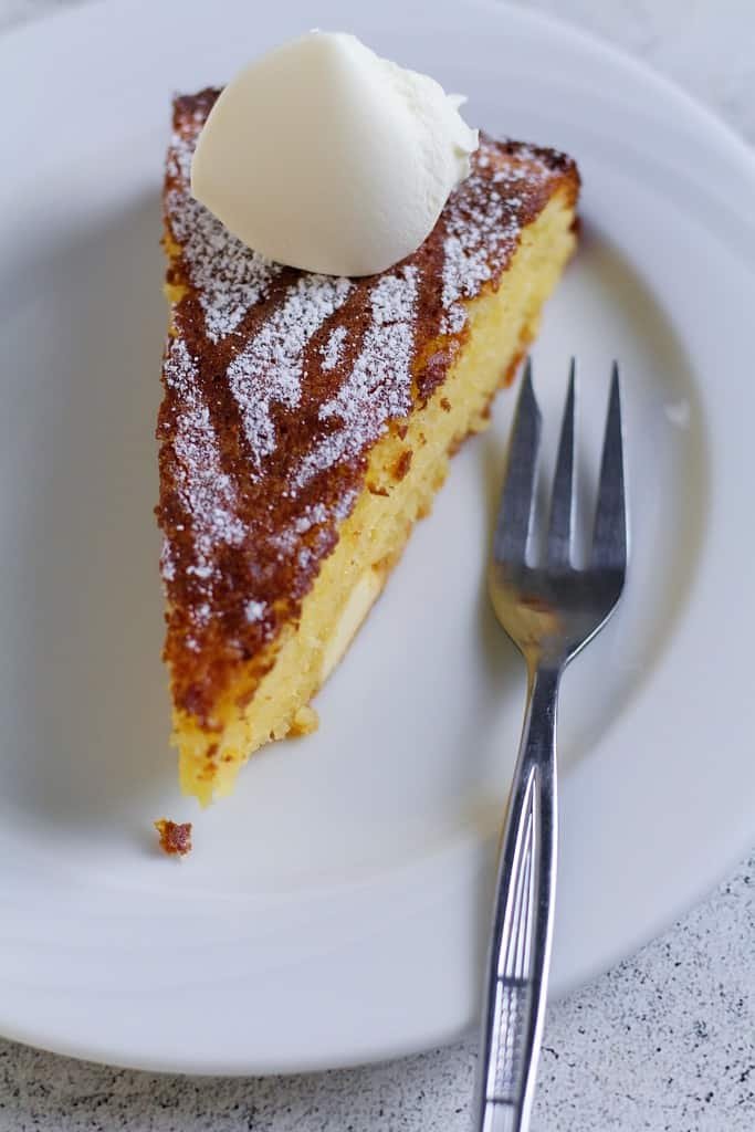 A slice of Capri lemon cake on a plate with a dollop of cream on top.