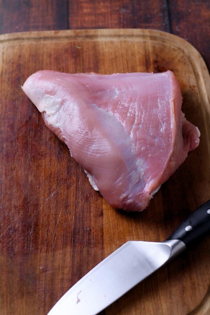 Turkey breast on a wooden cutting board.