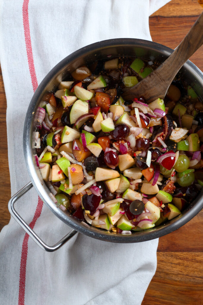 A photo of diced apples, plums, figs and grapes in a saucepan to make fruit chutney.
