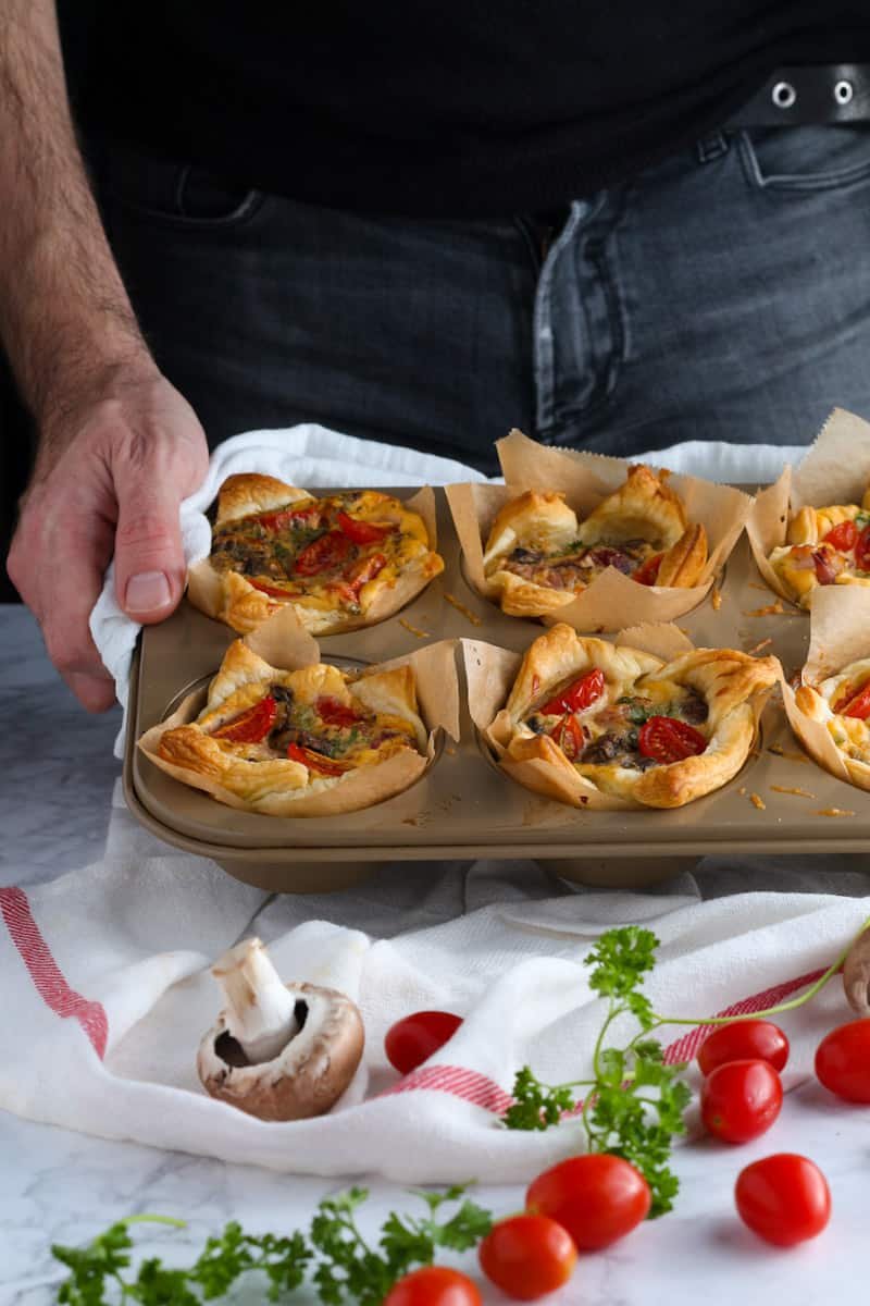 Jay holding a muffin tin of Puff Pastry Mini Quiches.