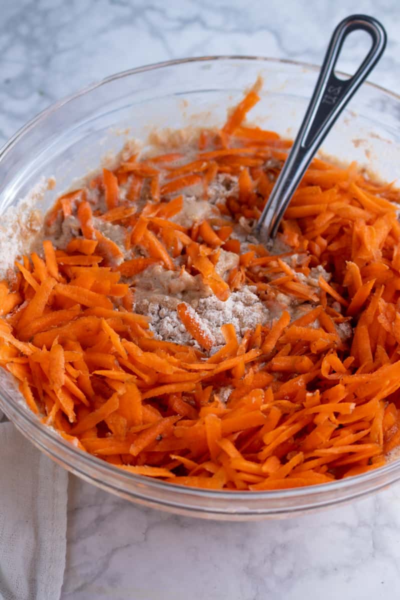 Ingredients for Easter Bunny Cupcakes being mixed in a mixing bowl with grated carrots on top.