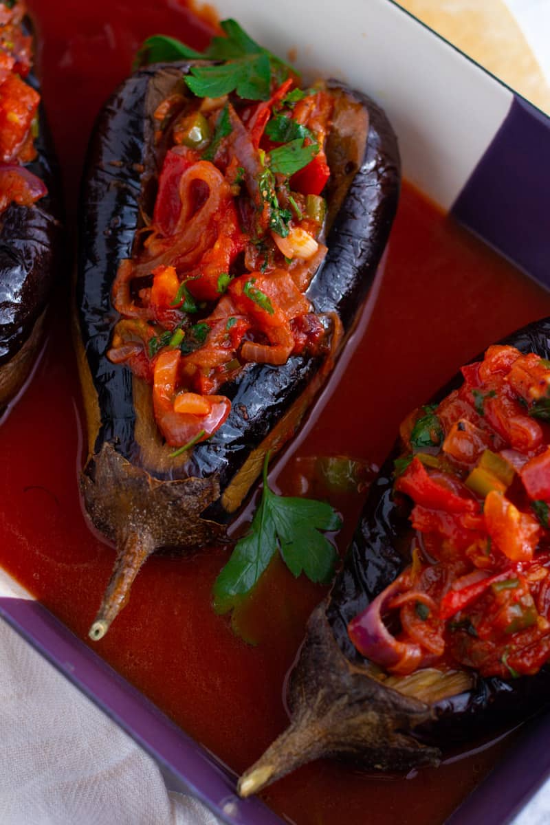 Stuffed eggplants with tomato sauce and herbs in a baking dish.
