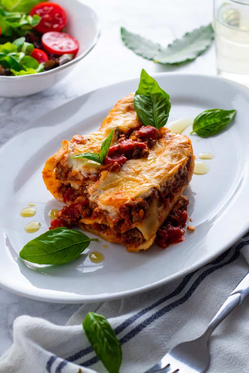 Beef cannelloni pasta filled with rich beef ragu and topped with bechamel sauce on a plate