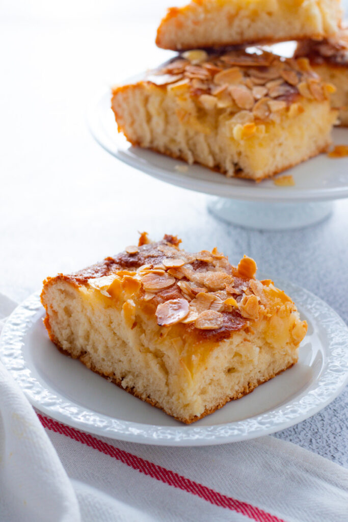 A slice of butterkuchen with a pile of butterkuchen behind.