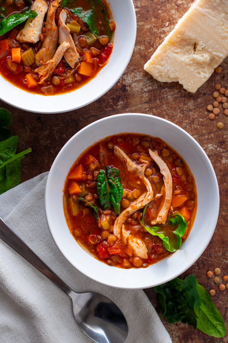 Two bowls of chicken and lentil soup seen from above.
