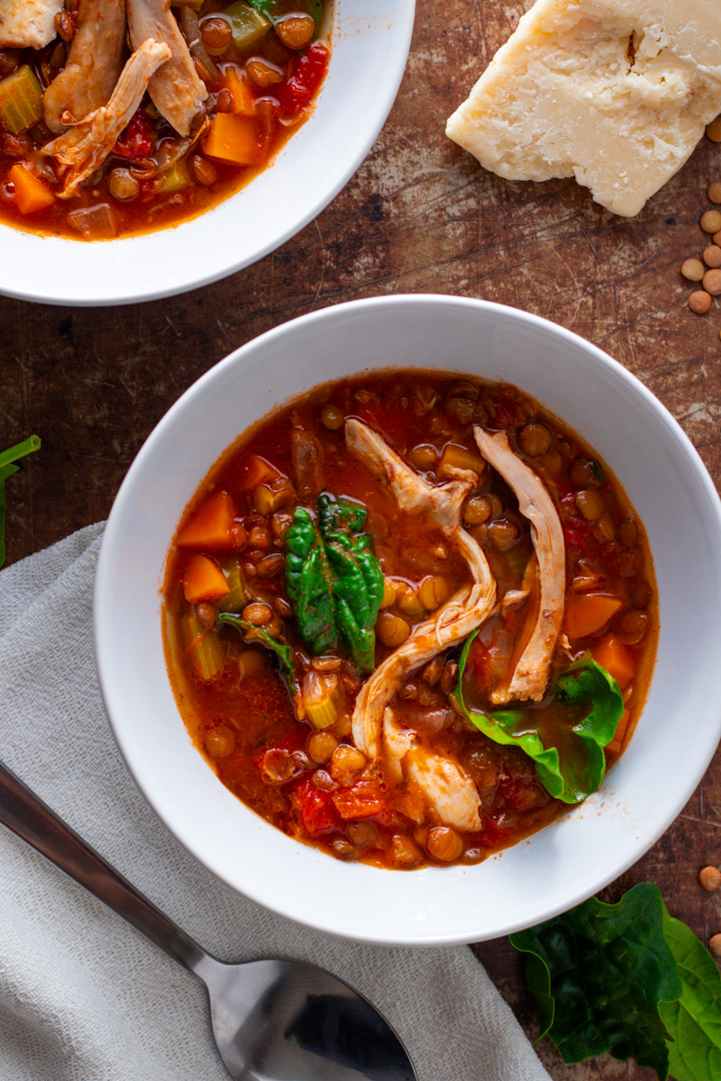 Two bowls of chicken and lentil soup seen from above.