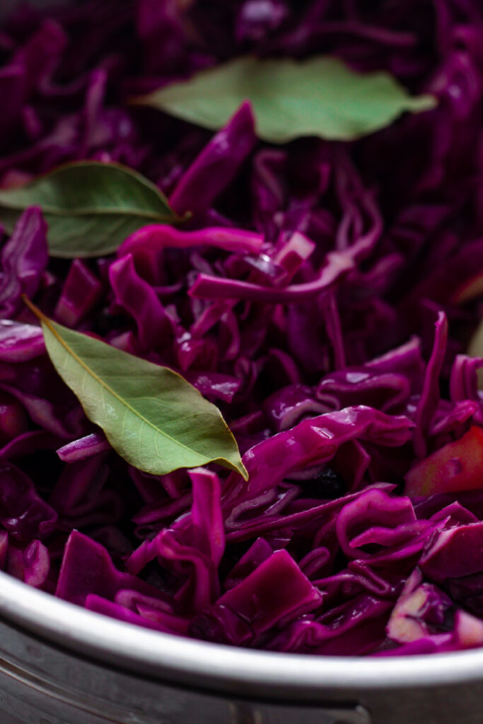 Sliced red cabbage with bay leaves in a saucepan.