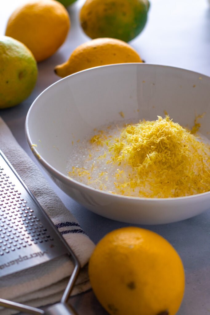 Grater and lemon zest with sugar in a bowl.