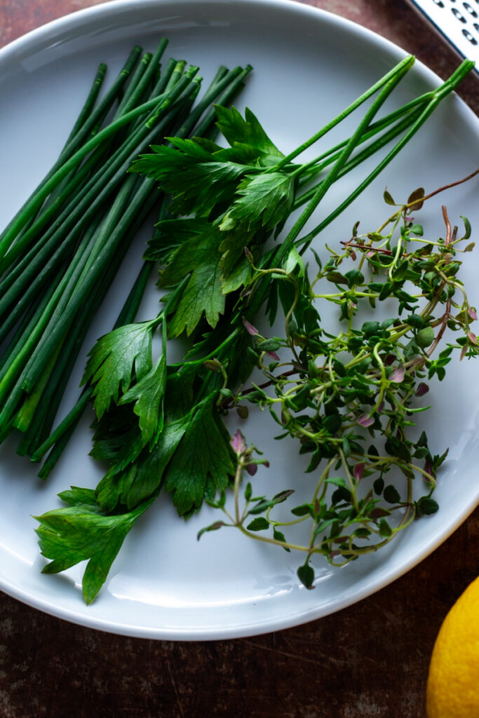 Fresh Herbs on a plate, from left, chives, parsley, thyme.