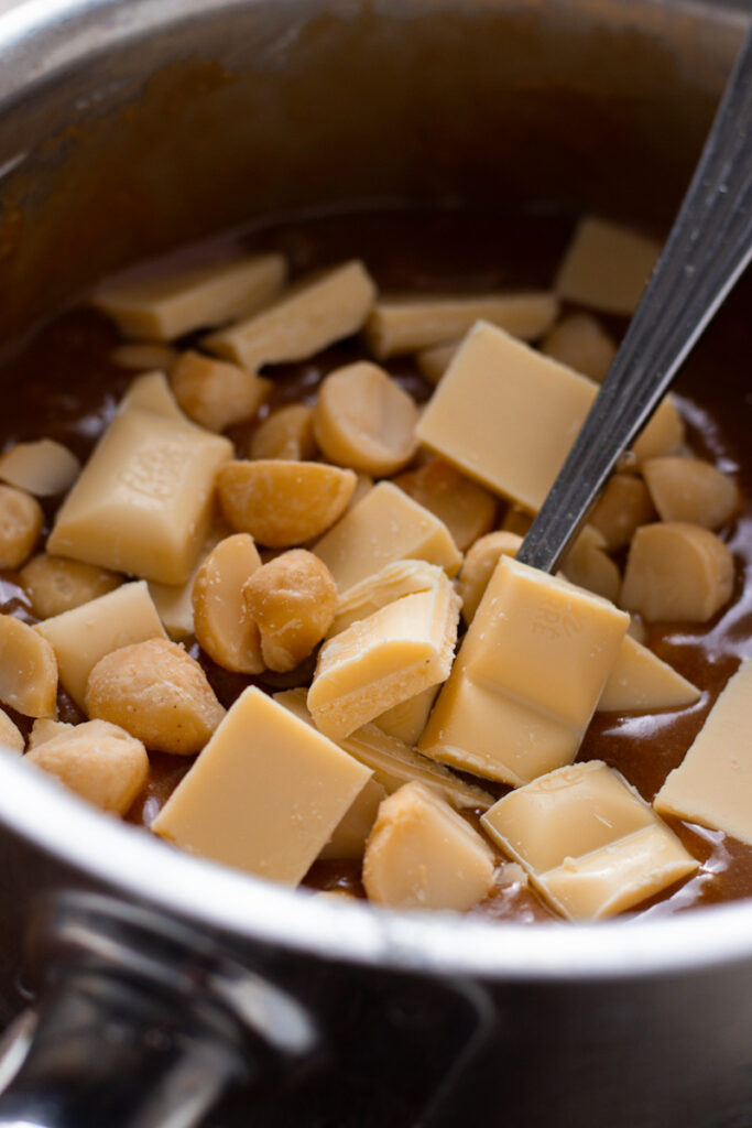 White chocolate and macadamias being mixed into blondie batter.