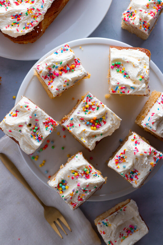Vanilla cake slices on a cake stand seen from above with sprinkles on top.