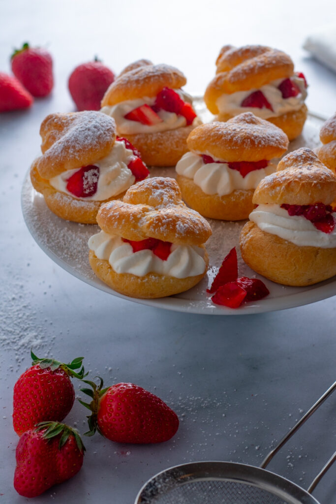 Filled Strawberry Cream Puffs on a cake stand.