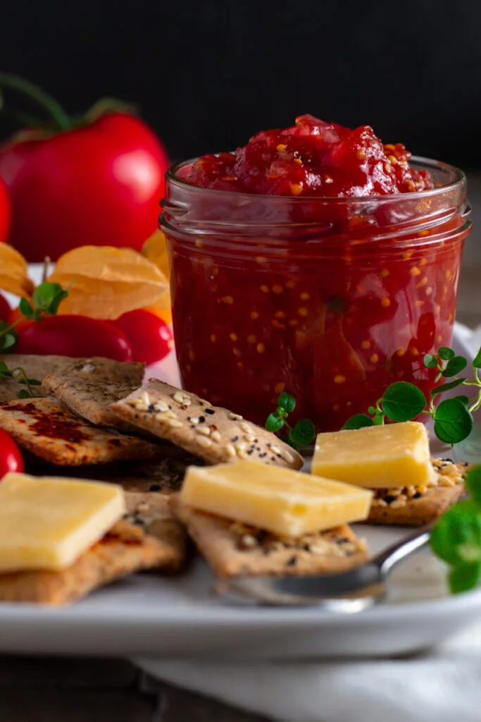 A jar of homemade tomato relish on a cheese board.