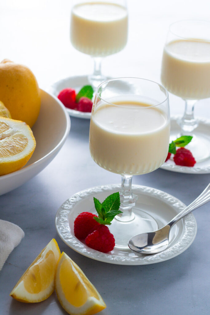 Lemon Posset in a glass with fresh berries, mint and lemon slices.