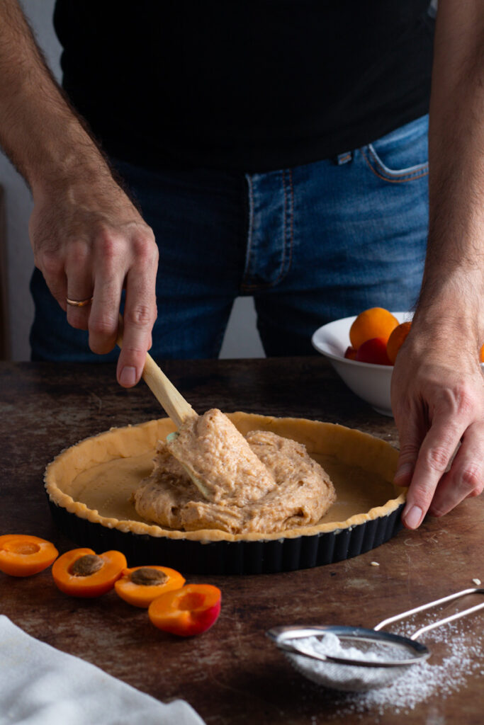 Jay spreading frangipane filling into tart case.