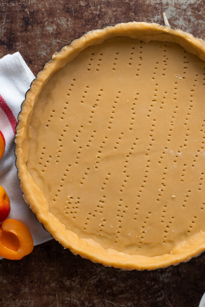 A lined tart pan that has been docked.