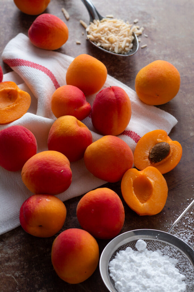 Apricots, almonds and powdered sugar on a table.