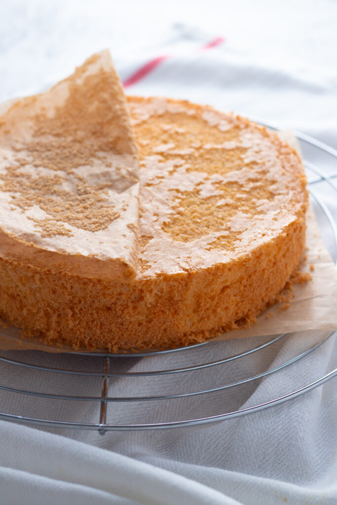 Sponge cake with baking paper being peeled off.