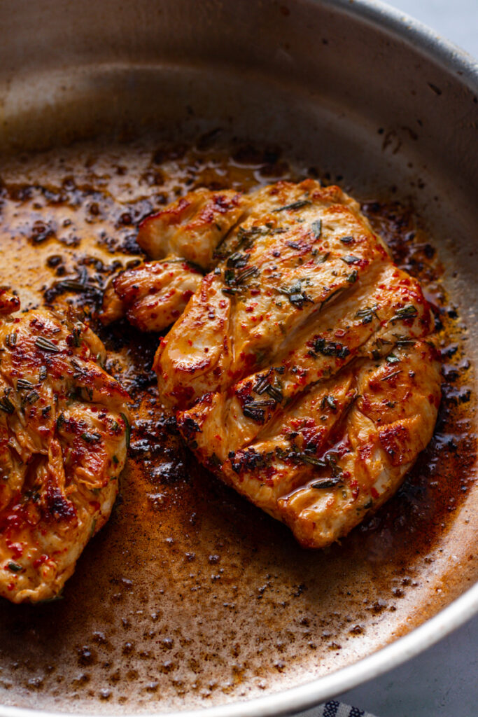 Golden brown cooked chickn breasts in a frying pan.