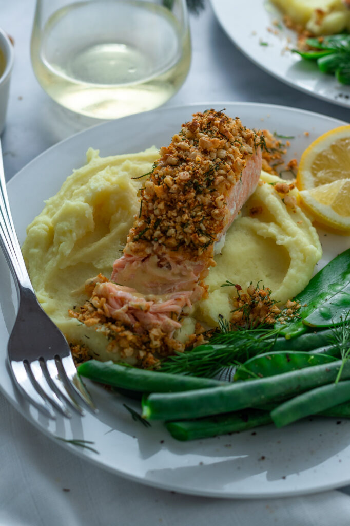 Hazelnut Crusted Salmon on a plate with mashed potatoes, beans and snowpeas.