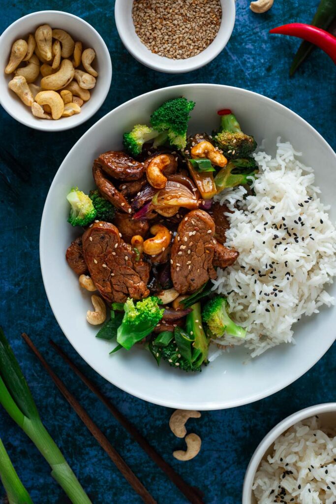 Easy Pork Stir Fry seen from above with bowls of sesame cashews and rice around.