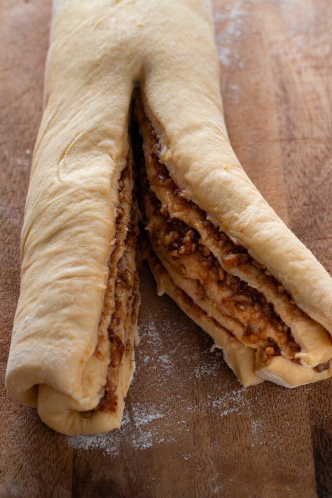 Nut filling spread on dough for Nusszopf, slicing the dough.