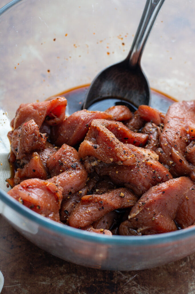 Marinating pork strips in a soy sauce.