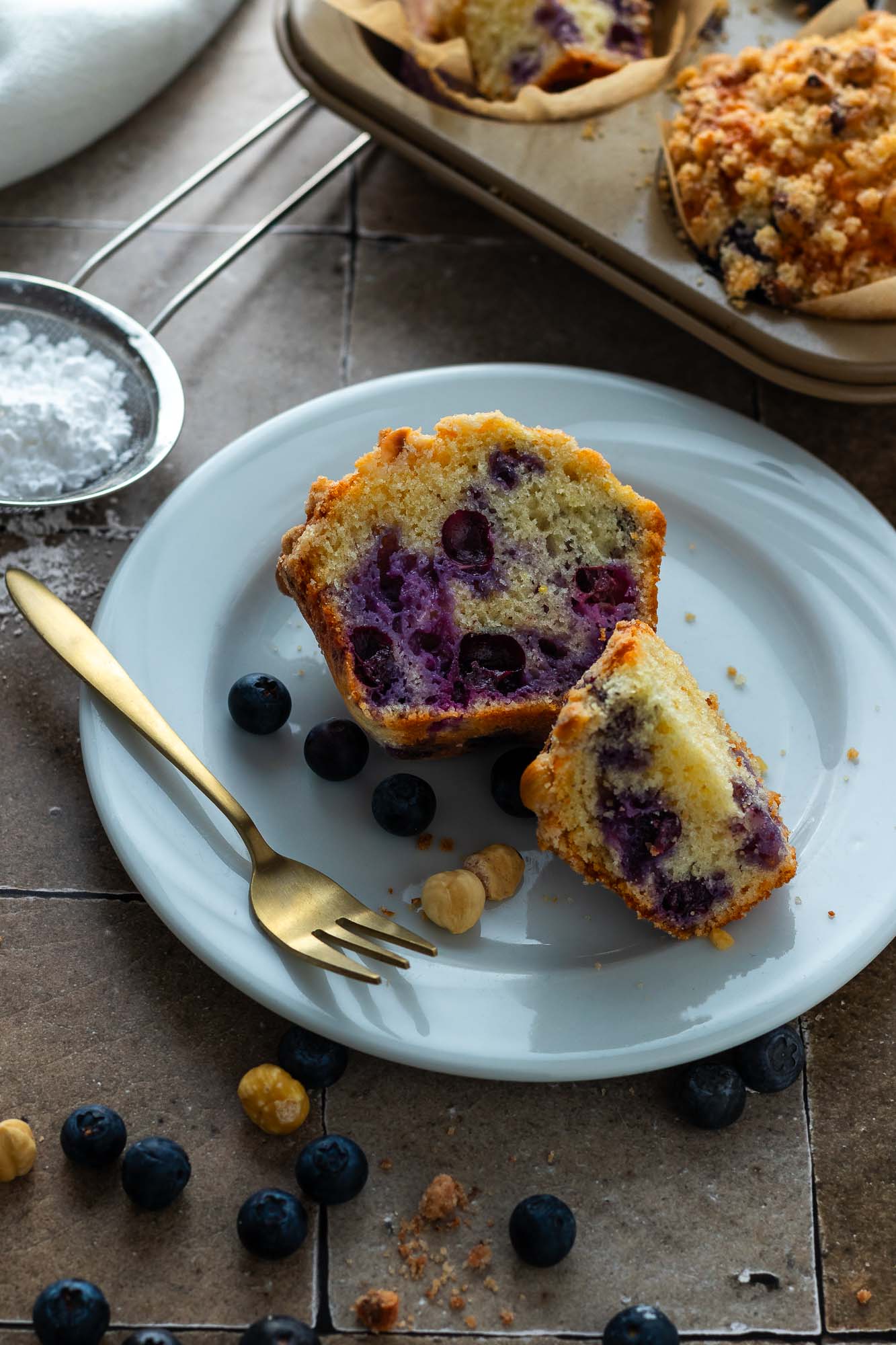 A blueberry streusel muffin on a plate, cut in half showing the crumb.