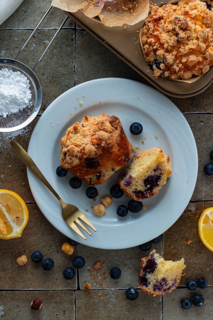 A blueberry streusel muffin on a plate, cut in half showing the crumb.