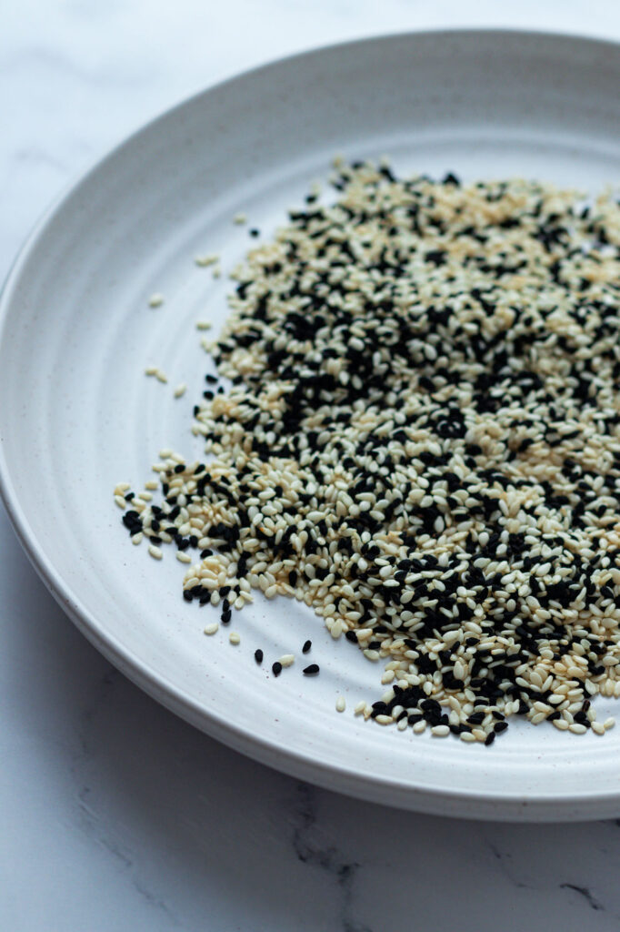 White and black sesame seeds on a plate.