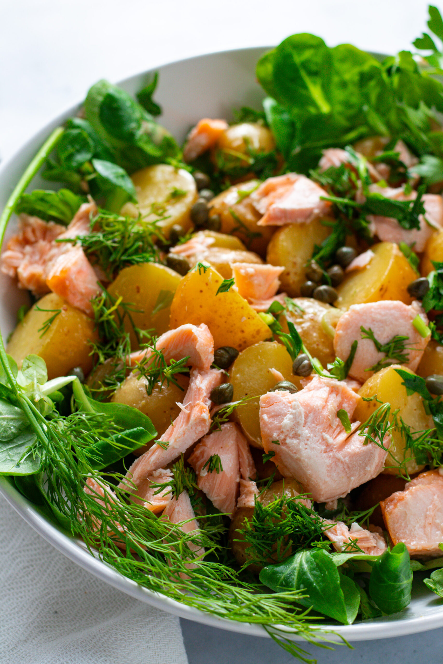 Warm potato salad with roasted salmon in a bowl.