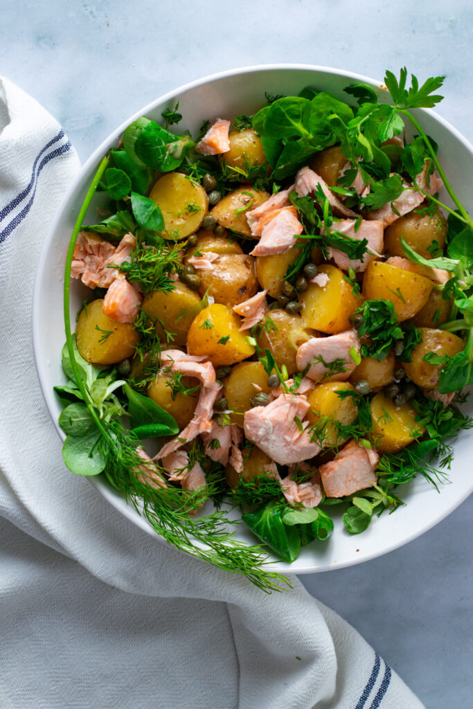 Warm potato salad with roasted salmon in a bowl.