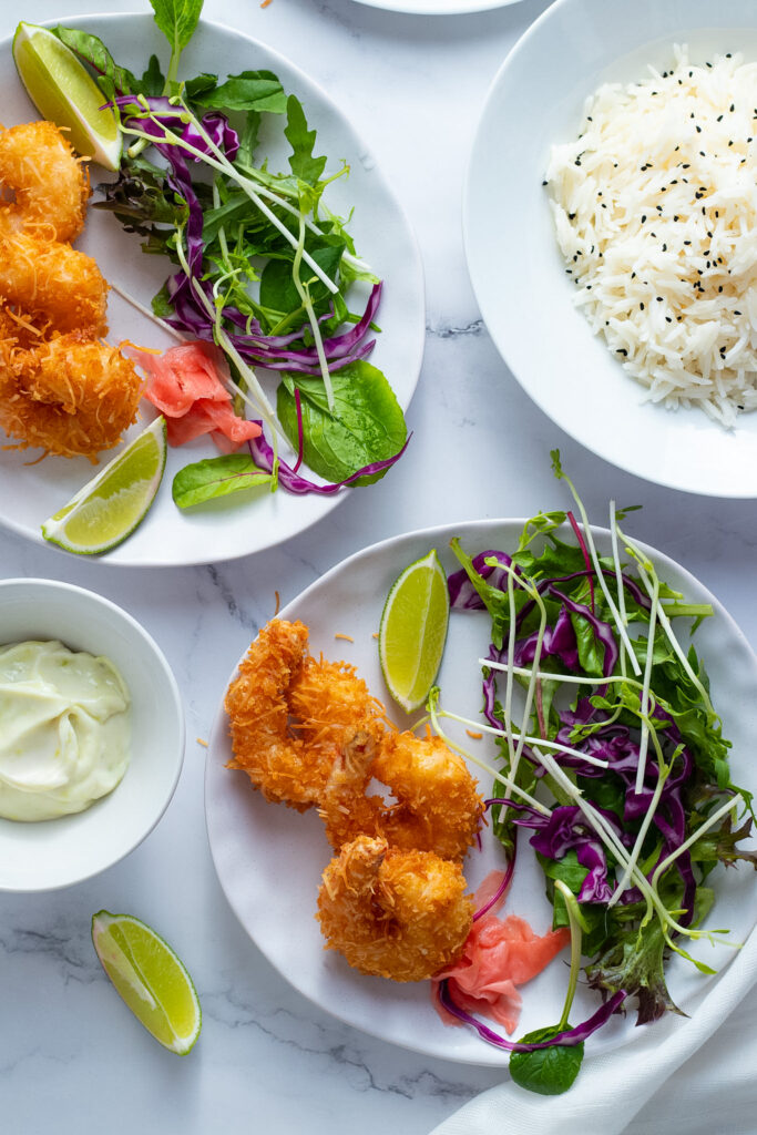 Panko Coconut Fried Shrimp on a plate with salad and lime wedges.