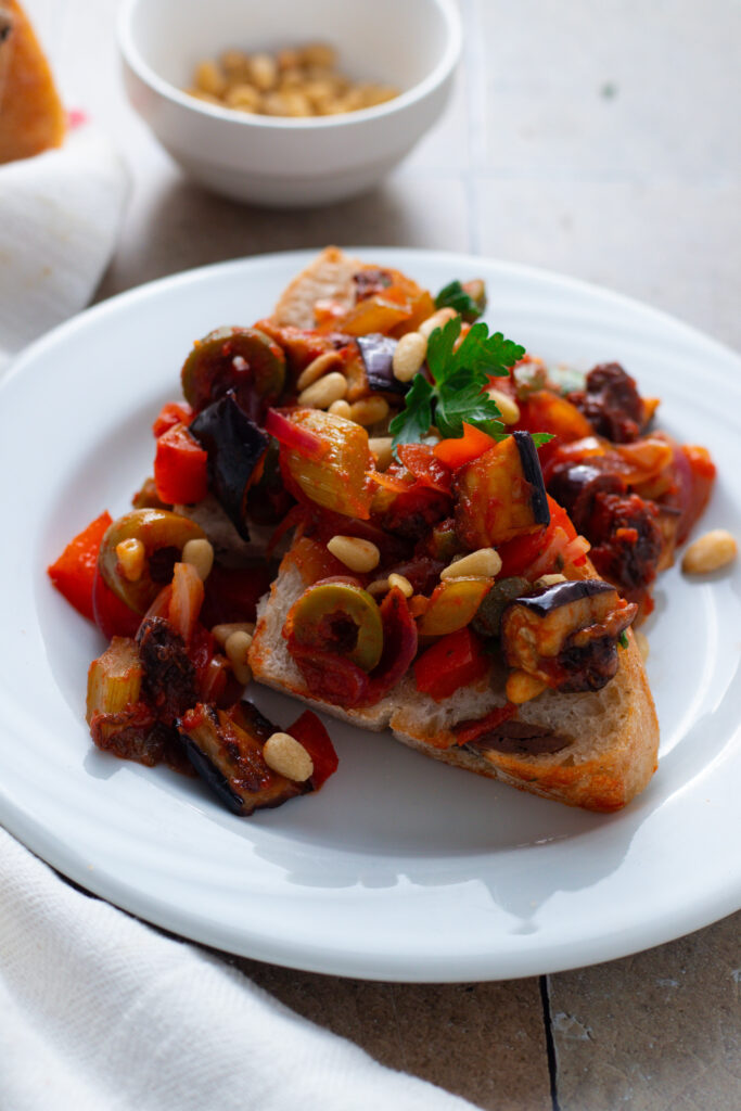 Caponata on olive bread on a plate.