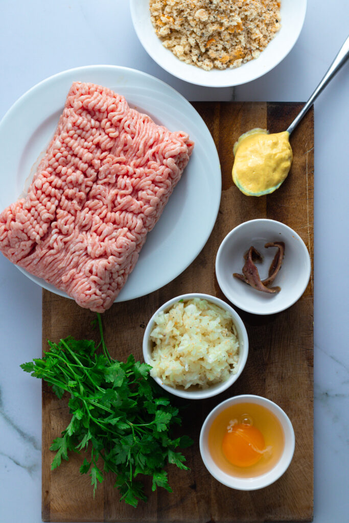 Ingredients for Königsberger Klopse: ground meat, breadcrumbs, egg, anchovies, parsley, mustard, and onion.