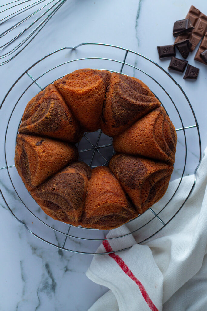 Freshly baked Marmorkuchen (German Marble Cake) cooling on a wire rack with chocolate pieces.