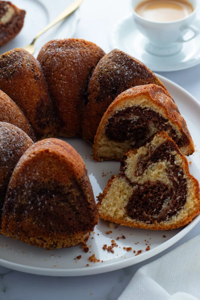 Marble cake slices on plates with coffee and chocolate. Marmorkuchen, a German cake with a swirled pattern.