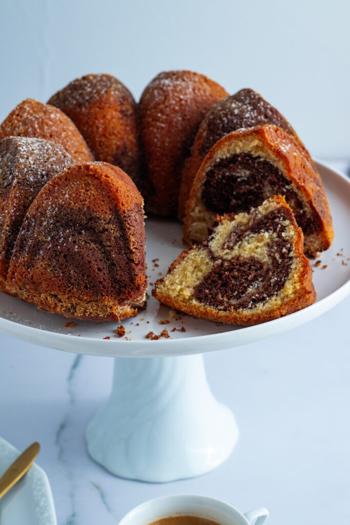 Marble cake on a white stand, slice cut to show the marbled interior.